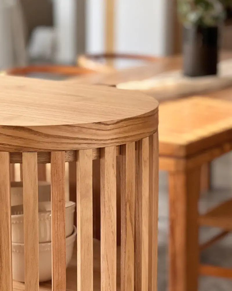 Mesa auxiliar redonda hecha con listones de madera.