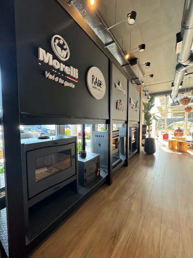 Salón comercial con estufas en exhibición, piso de madera y luminarias sobre rieles.